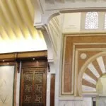 Mosque interior detail: golden slatted ceiling, inlaid wooden doors and the mihrab arch