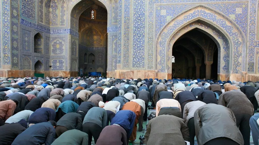 Filas de hombres en postración durante el salat en el patio de una mezquita alicatada