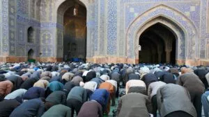 Filas de hombres en postración durante el salat en el patio de una mezquita alicatada