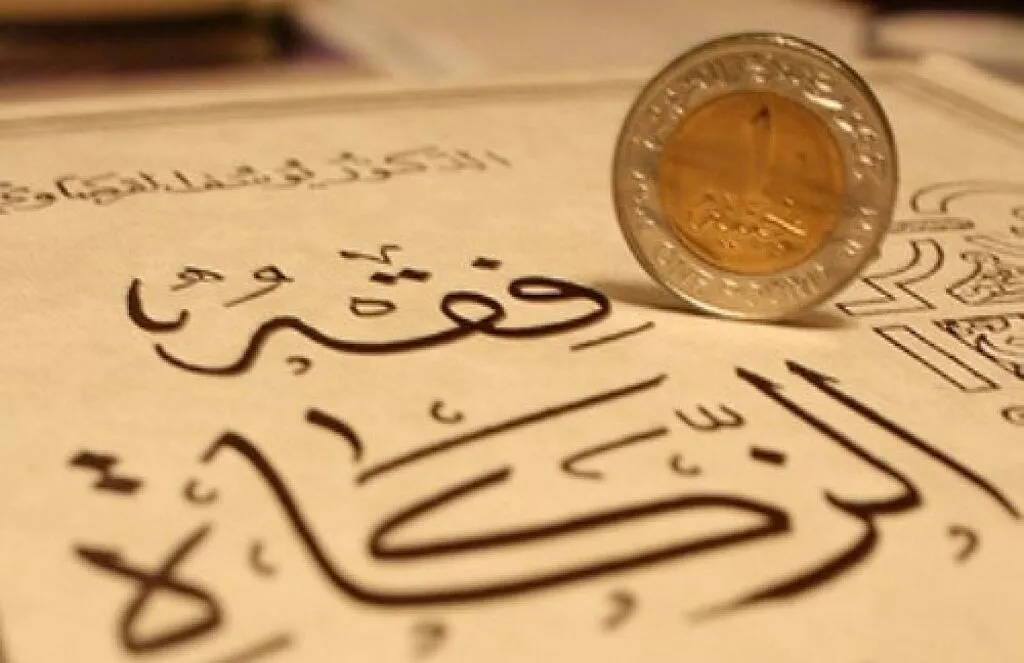 Moneda de metal apoyada sobre una hoja con caligrafía árabe trazada en tinta oscura