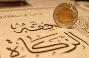 Moneda de metal apoyada sobre una hoja con caligrafía árabe trazada en tinta oscura