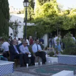 Público sentado en el jardín de la Mezquita junto a la fuente alicatada y las alfombras