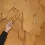 Una mano señala con una vara las piezas de mocárabes del techo del zaguán