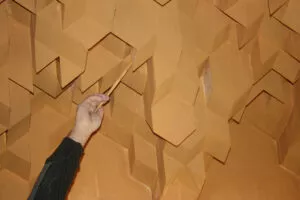 Una mano señala con una vara las piezas de mocárabes del techo del zaguán