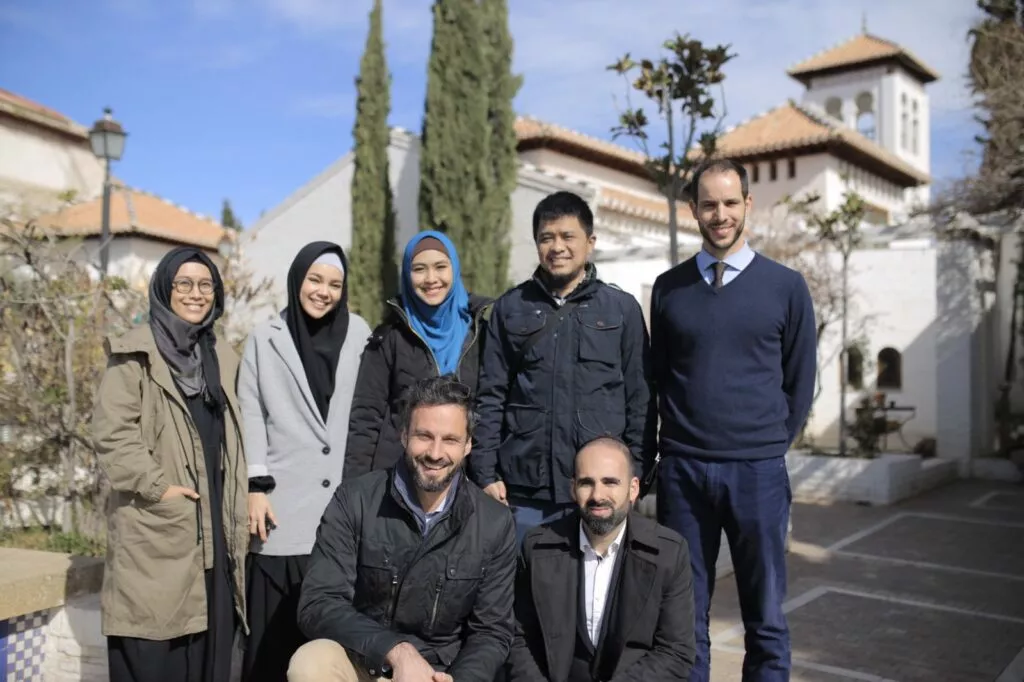 Grupo de visitantes posando en el patio de la Mezquita, con la torre y los cipreses al fondo