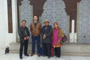 Indonesian visitors and a mosque representative in front of the blue tiled facade of the mosque