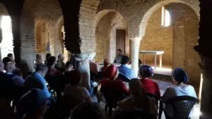 Charla en una sala de arcos de herradura de ladrillo con el ponente en la mesa y el público sentado