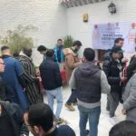 Hombres en el patio de la mezquita recogiendo ejemplares del Corán bajo la pancarta del reparto