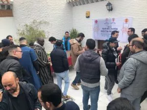 Hombres en el patio de la mezquita recogiendo ejemplares del Corán bajo la pancarta del reparto