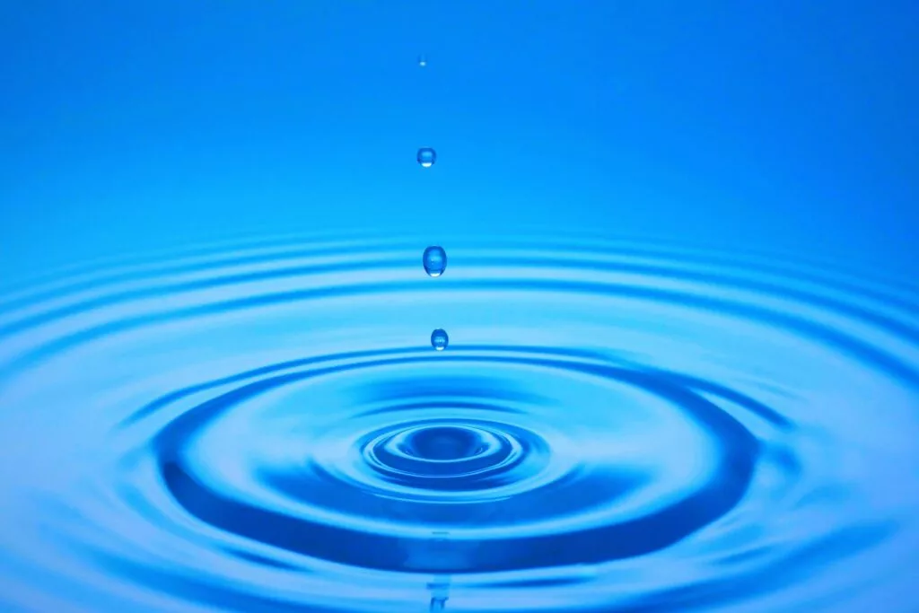 Gota de agua cayendo sobre una superficie azul y las ondas concéntricas que forma