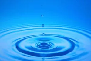 Gota de agua cayendo sobre una superficie azul y las ondas concéntricas que forma