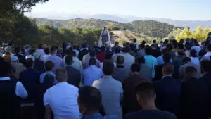 Imam predicando ante una gran multitud sentada al aire libre, con Sierra Nevada al fondo