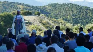 Jatib leyendo la jutba del Eid al aire libre ante los fieles, con los montes al fondo