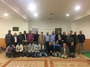 Unos treinta hombres posan de pie y arrodillados sobre las alfombras de una sala de oración