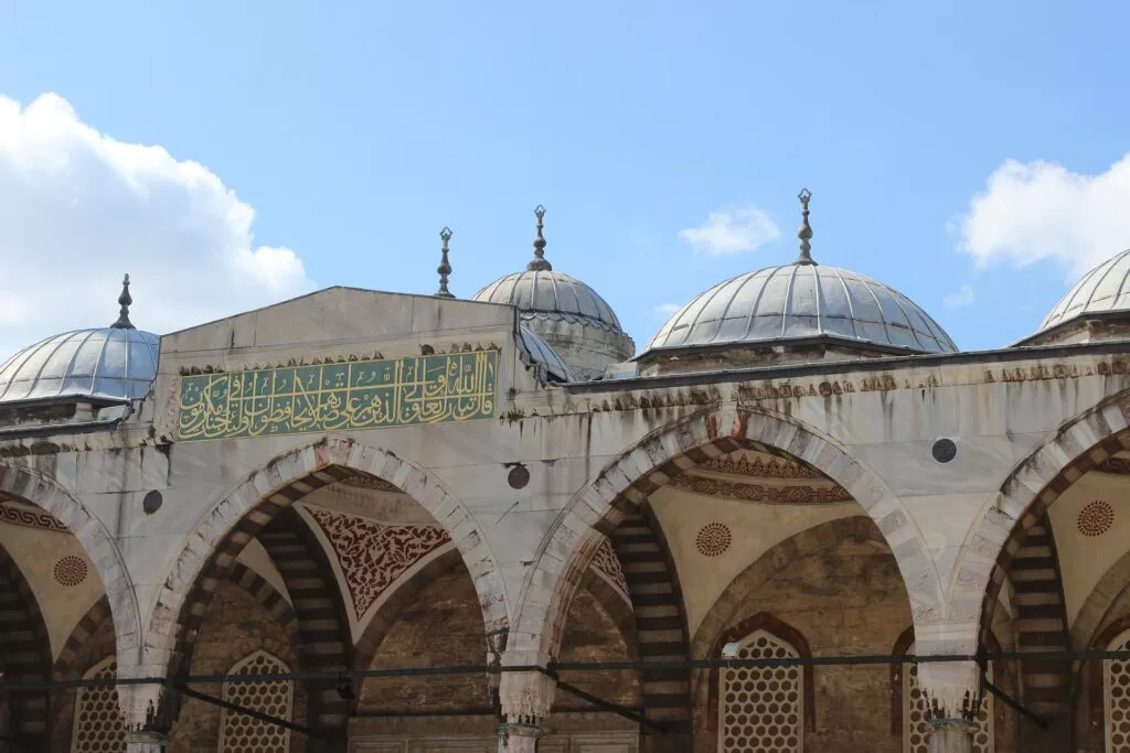 Cúpulas de plomo y arcos de una mezquita otomana con una banda de caligrafía árabe en verde y oro