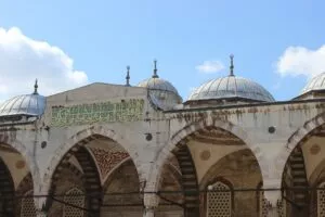 Cúpulas de plomo y arcos de una mezquita otomana con una banda de caligrafía árabe en verde y oro