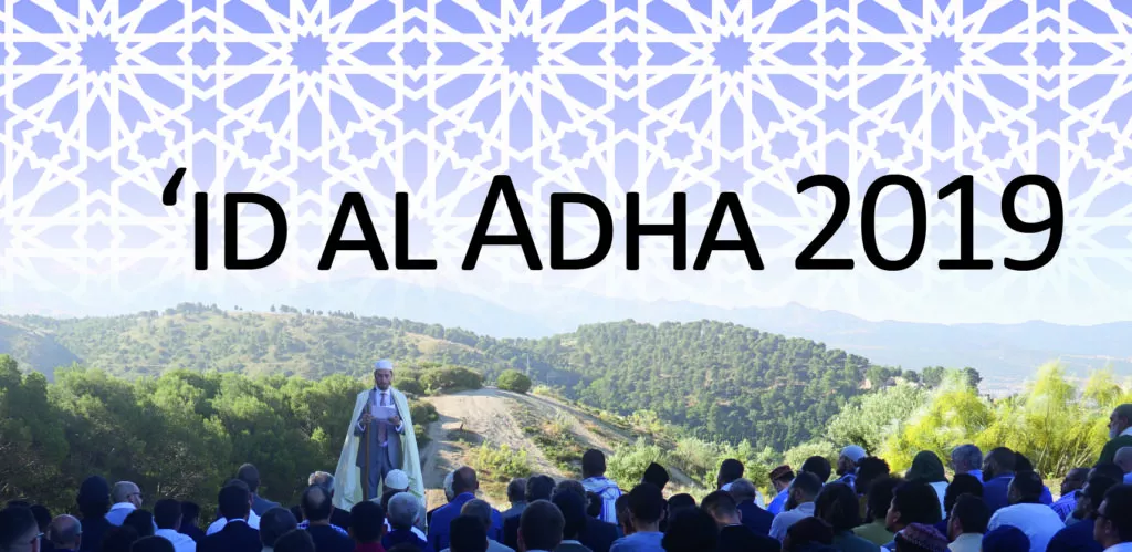 'Id al Adha 2019 poster over the outdoor prayer, the imam in white before the seated congregation