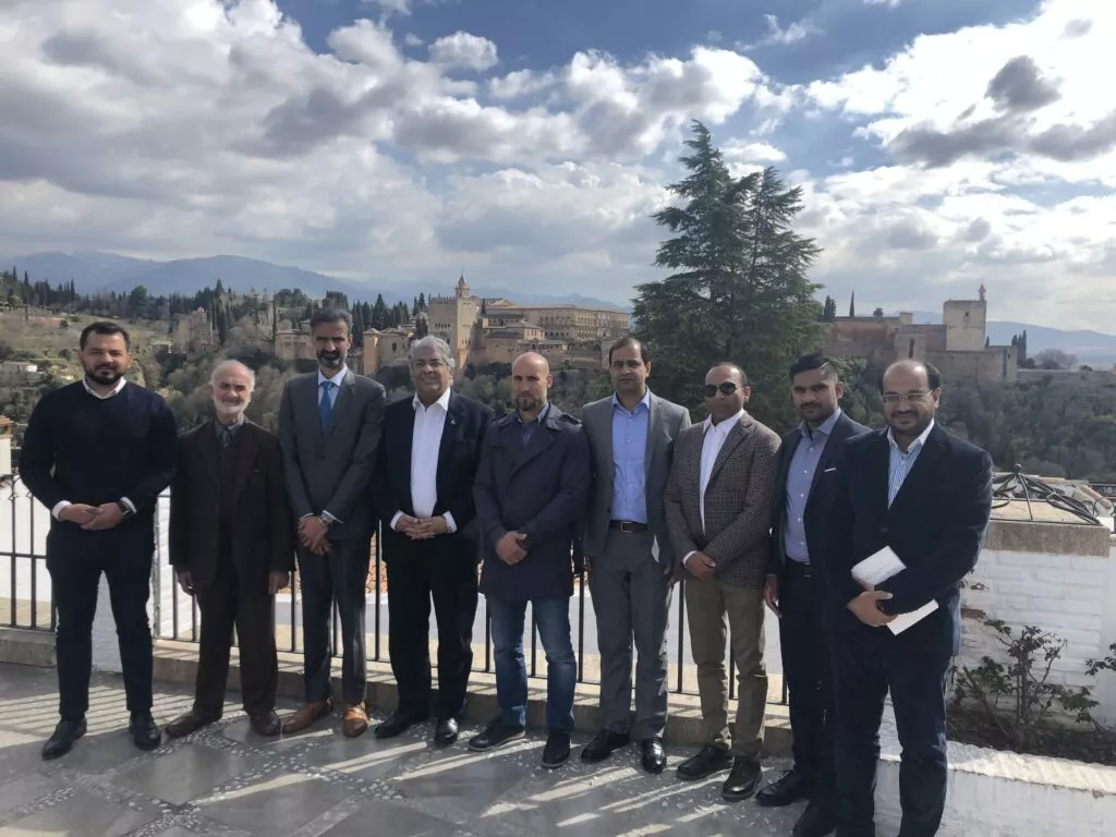 Nueve hombres con traje posan en un mirador del Albaicín con la Alhambra y Sierra Nevada al fondo