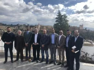 Nueve hombres con traje posan en un mirador del Albaicín con la Alhambra y Sierra Nevada al fondo