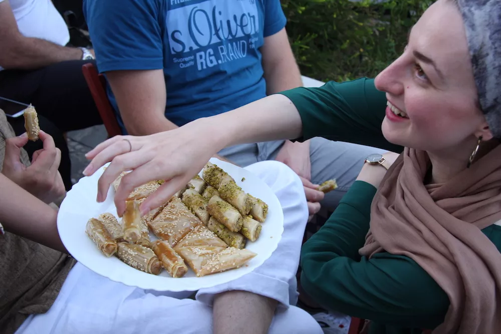 Una asistente ofrece una bandeja de dulces de hojaldre con pistacho y sésamo durante la celebración