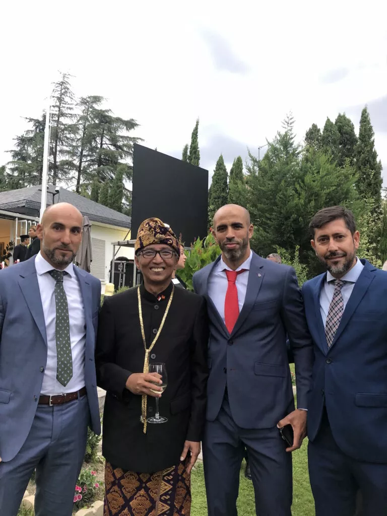 Cuatro invitados posan en el jardín durante la recepción en la embajada, uno de ellos con traje tradicional indonesio