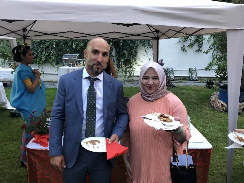 Dos invitados posan con sus platos bajo la carpa del catering durante la recepción