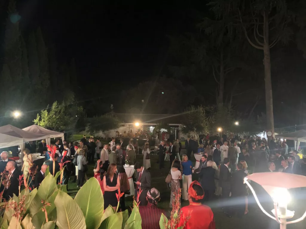 Vista nocturna del jardín de la embajada durante la recepción, con los invitados de pie entre las carpas