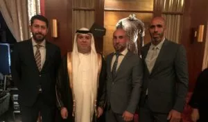 Cuatro hombres posan juntos en una recepción, uno de ellos con túnica blanca y pañuelo del Golfo