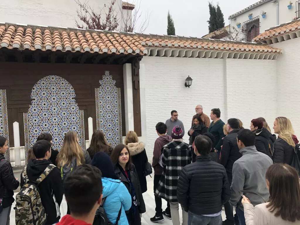 Grupo de estudiantes de visita escuchando la explicación en el patio, junto a la portada alicatada de la mezquita
