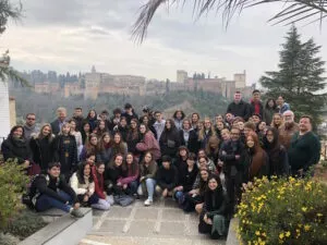 Grupo numeroso de estudiantes posa en el jardín de la mezquita con la Alhambra al fondo