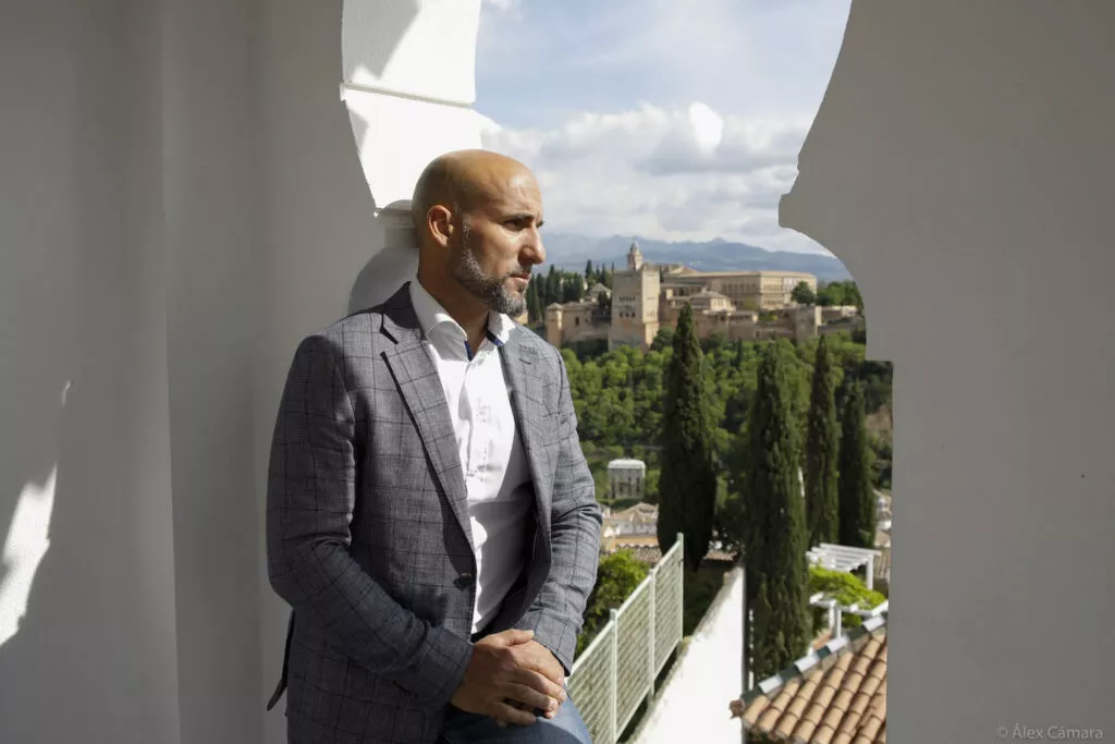 Un hombre apoyado en el vano del mirador mira hacia la Alhambra