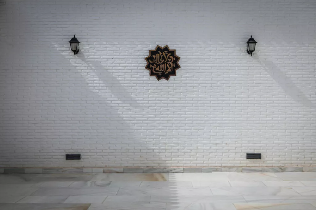 Muro encalado del patio con una placa caligráfica en forma de estrella y dos faroles