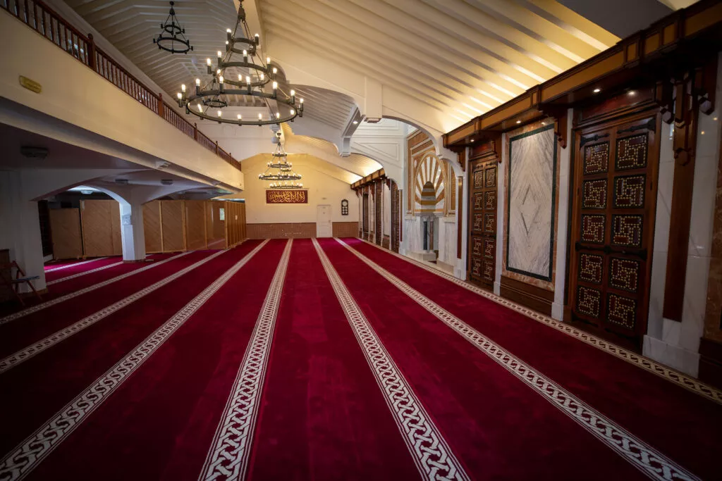 La sala de oración desde el fondo, con la galería superior, las lámparas de forja y el mihrab a la derecha