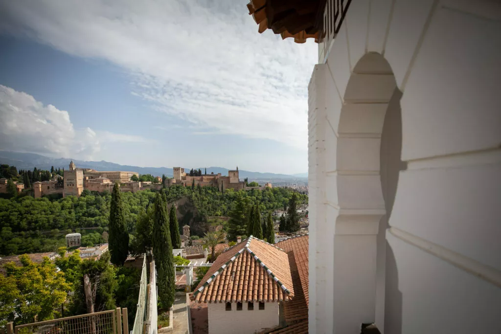 La Alhambra vista desde el porche de la mezquita, entre el arco encalado y los tejados del Albaicín