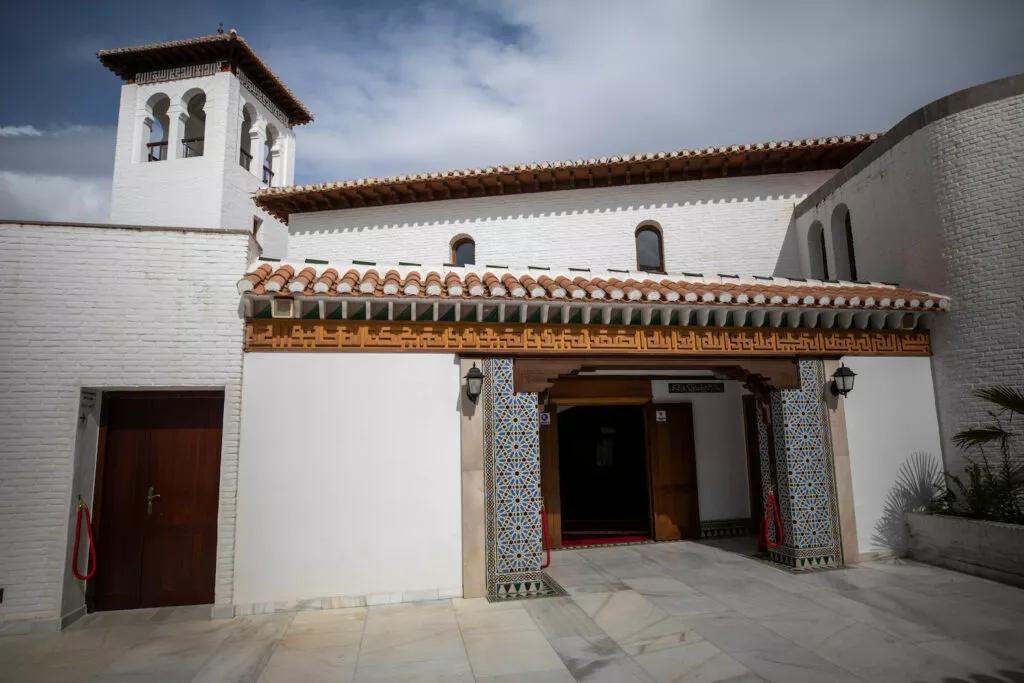 Fachada de entrada de la mezquita, con el alminar, el friso caligráfico y las jambas alicatadas