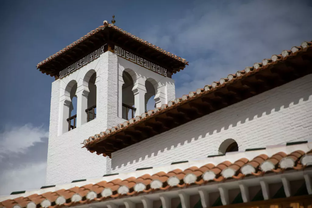 El alminar de la mezquita visto desde abajo, con sus arcos gemelos y el friso caligráfico bajo el alero