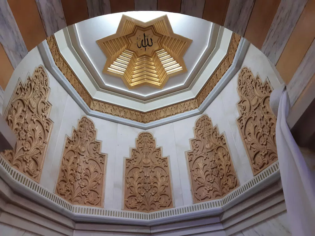 Cúpula de mocárabes vista desde abajo, con la estrella dorada central y el nombre de Allah en el centro