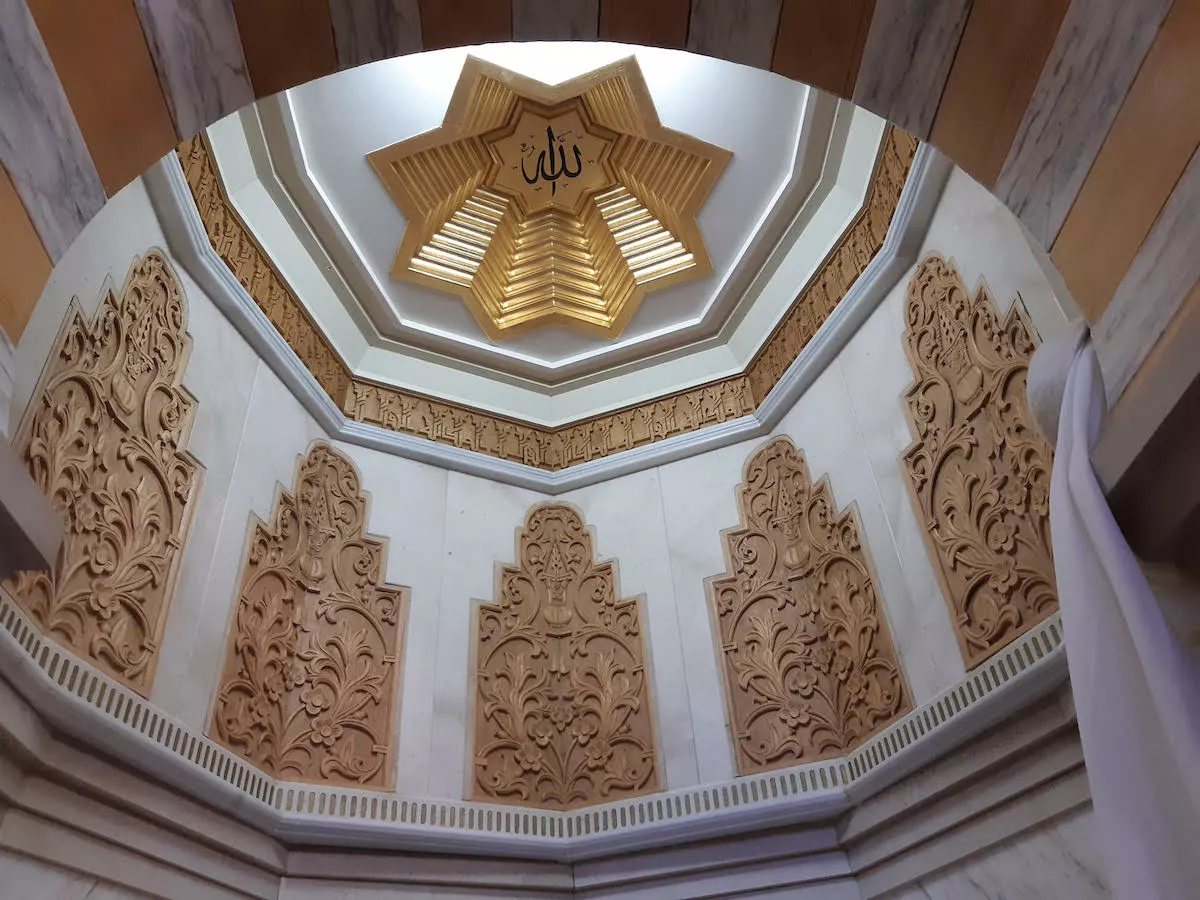 Cúpula de mocárabes vista desde abajo, con la estrella dorada central y el nombre de Allah en el centro