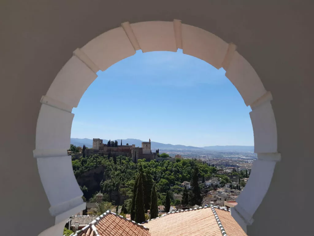 La Alhambra enmarcada por un óculo circular abierto en el muro de la mezquita