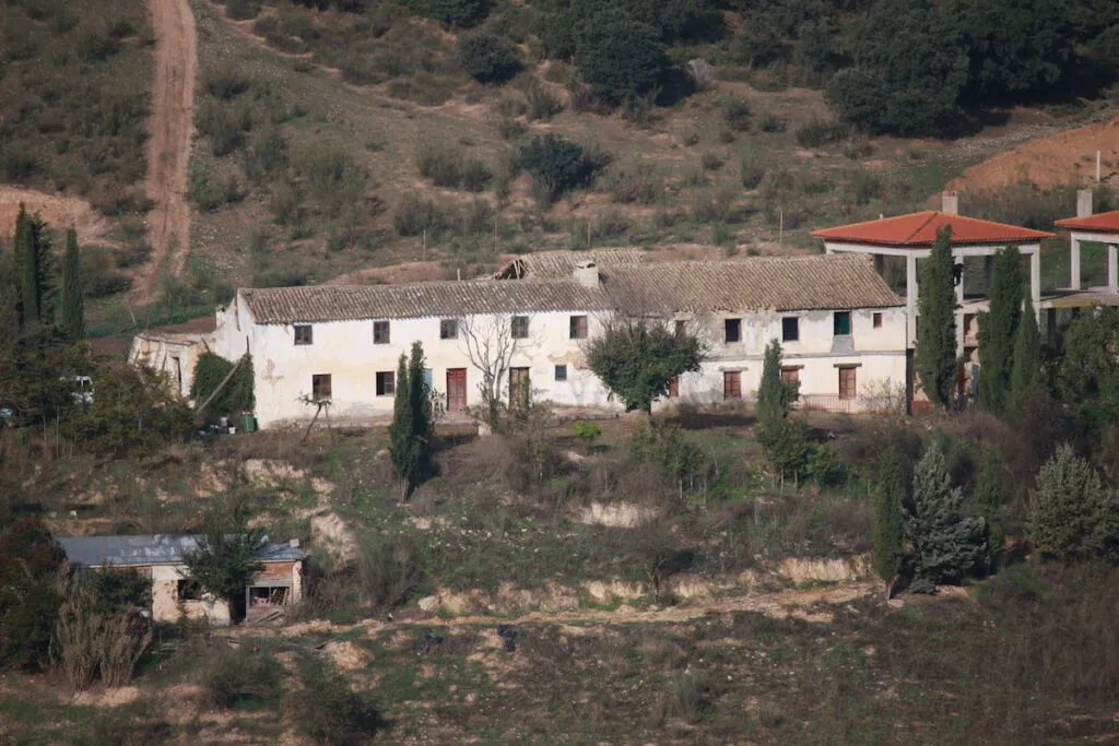 Vista de la alquería de Al-Kawthar, un caserío encalado de dos plantas en la ladera entre encinas