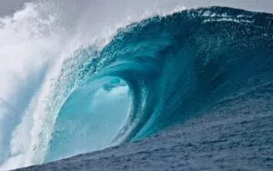 Gran ola de mar azul turquesa rompiendo y formando un tubo de espuma blanca