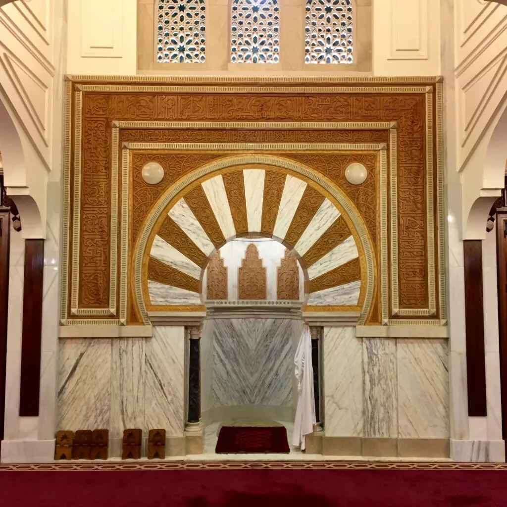 Mihrab de la mezquita con arco de herradura, yeserías doradas y mármol blanco