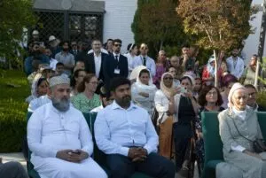 Público sentado y de pie en el jardín de la mezquita durante un acto al aire libre