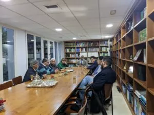 Reunión alrededor de una mesa larga en la biblioteca de la mezquita, con tetera y vasos de té