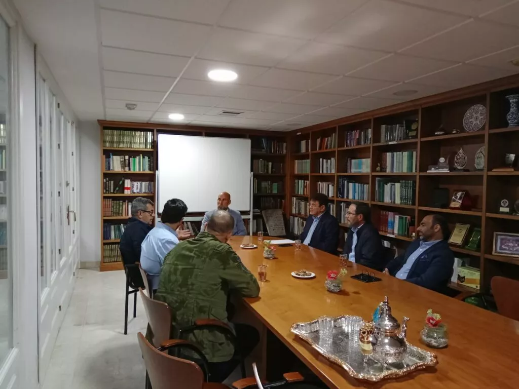 Reunión en la biblioteca de la mezquita, con los asistentes sentados alrededor de la mesa y una bandeja de té en primer término