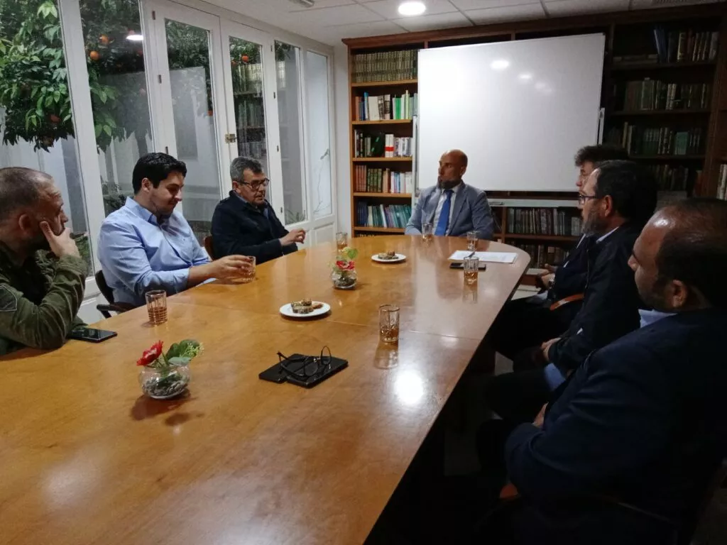 Los asistentes a la reunión conversan alrededor de la mesa de la biblioteca