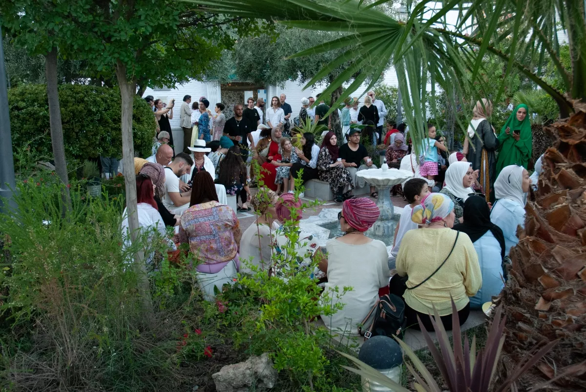 Asistentes conversando de pie y sentados alrededor de la fuente del jardín durante la celebración
