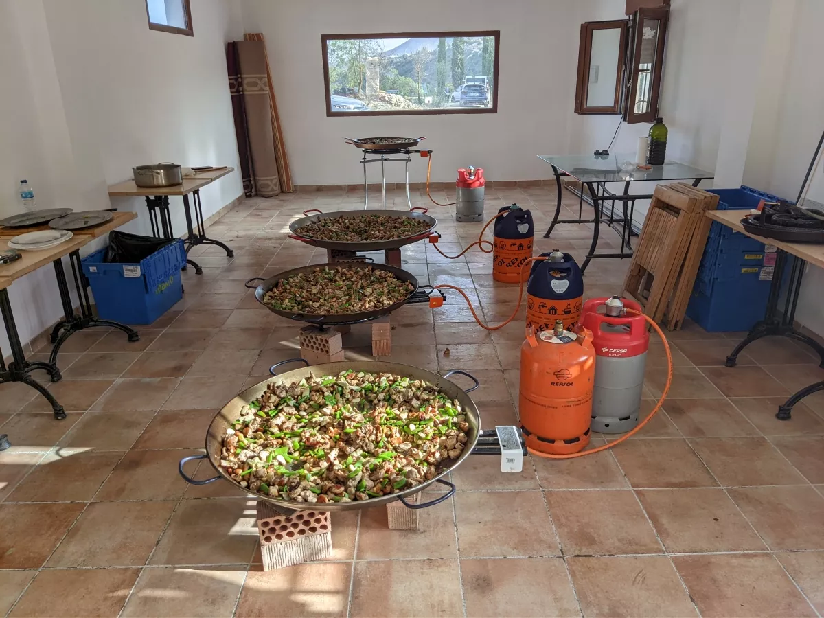 Tres paellas cocinándose sobre quemadores de gas en el interior de una sala