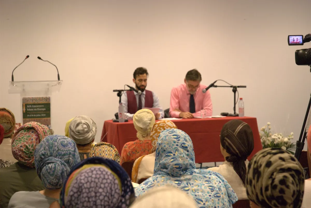 Dos ponentes en la mesa durante una sesión del XIX Encuentro Islam en Europa, con el público de espaldas