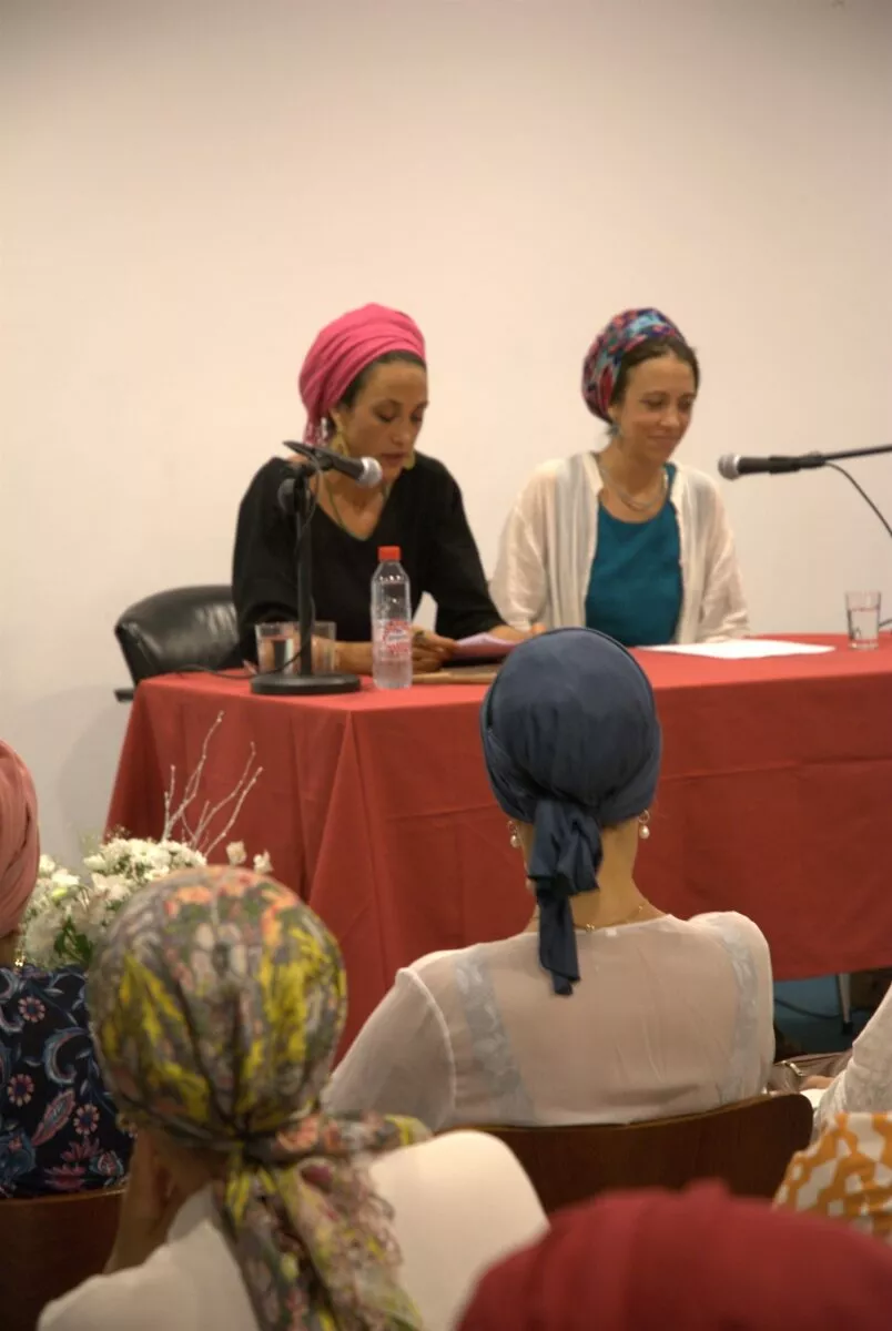 Dos ponentes hablan ante los micrófonos de la mesa durante el encuentro de mujeres